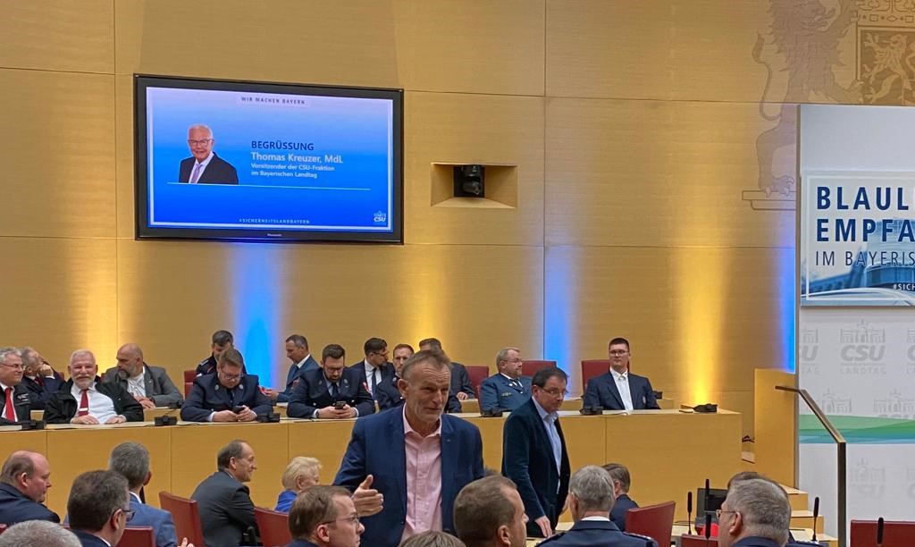 Sitzungssaal im bayerischen Landtag - Feuerwehrleute hinten sitzend. Vorne Abgeordnete - Stehend Hans Ritt